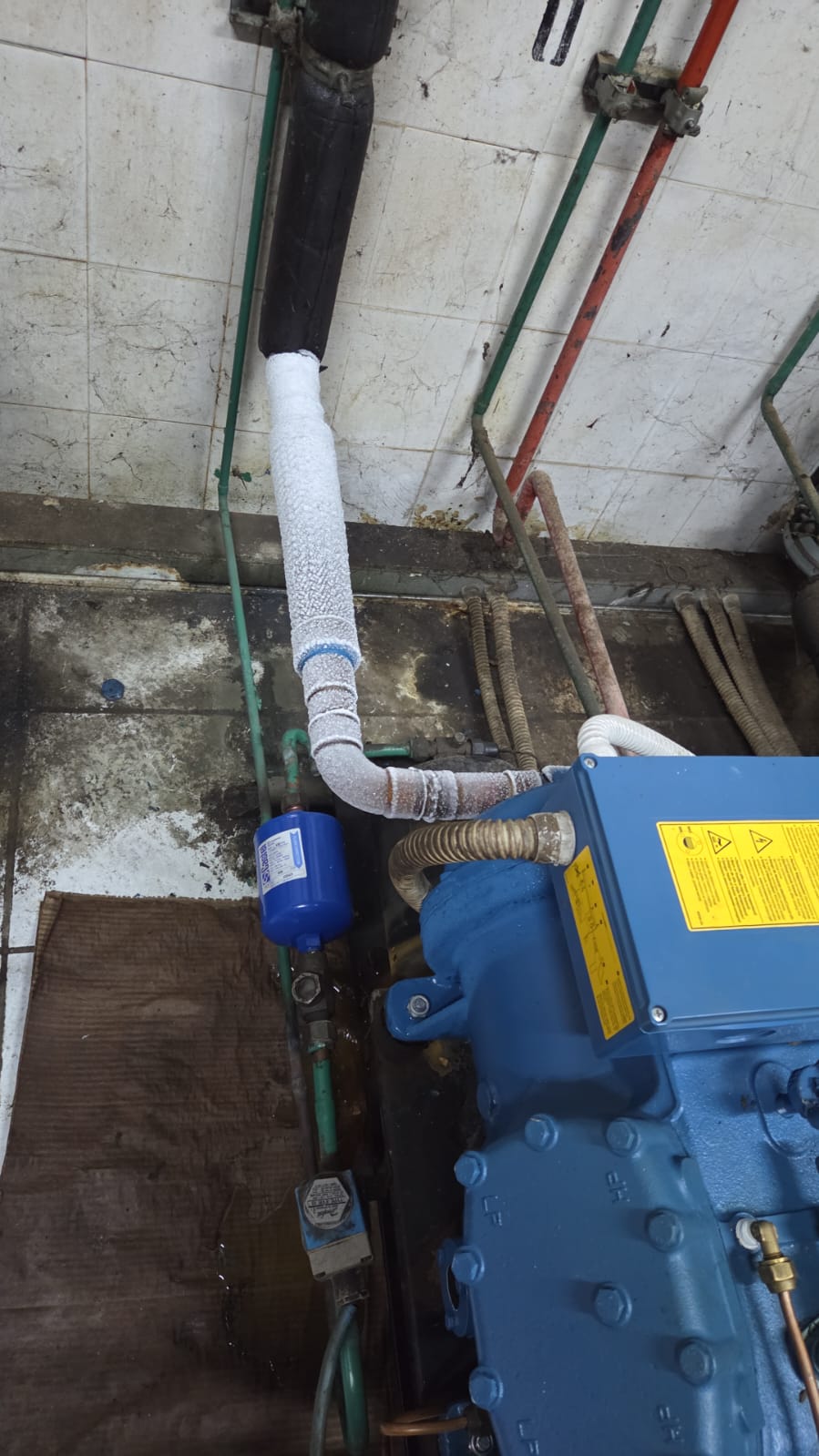 Centrale frigorifera con compressore e tubazioni coibentate in un locale tecnico