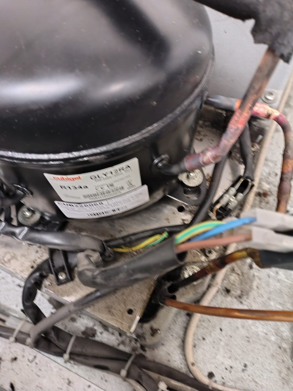 Compressore ermetico con i cablaggi elettrici durante un intervento di riparazione